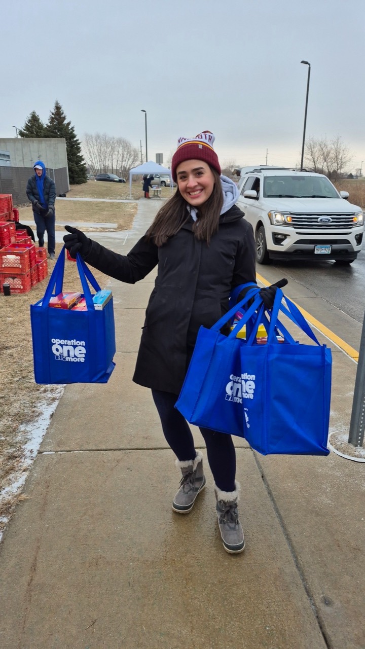 Volunteer carrying Operation One More grocery bags